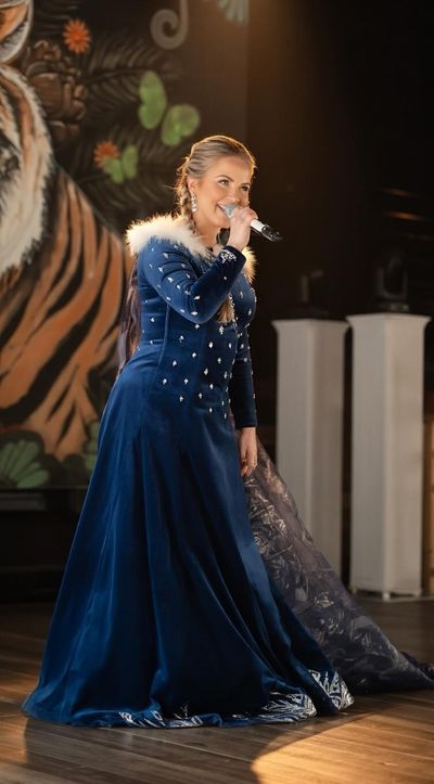 Chanteuse en robe bleue au micro, sur scène.